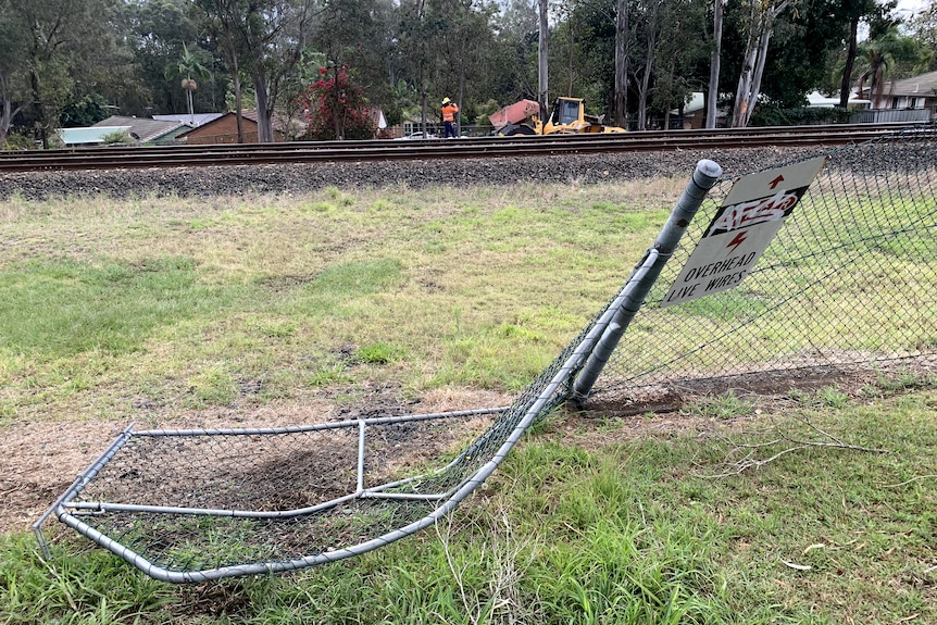 A fence is pushed over near rail tracks.