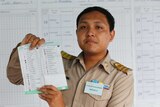 A Thai official wearing a karki uniform holds up a ballot sheet
