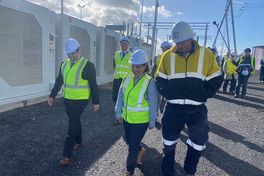 A group of people in high-vis inspecting a giant battery.