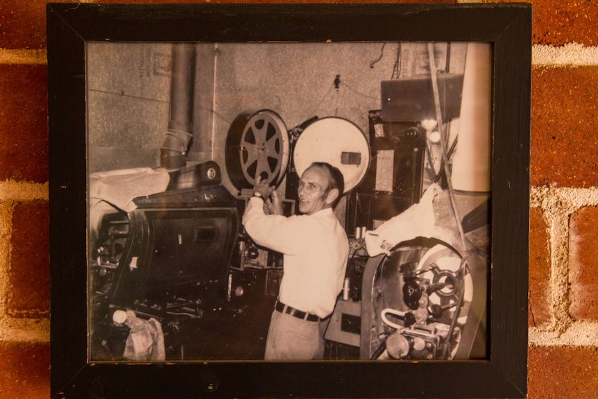 Framed photograph of a man standing in front of a film projector.