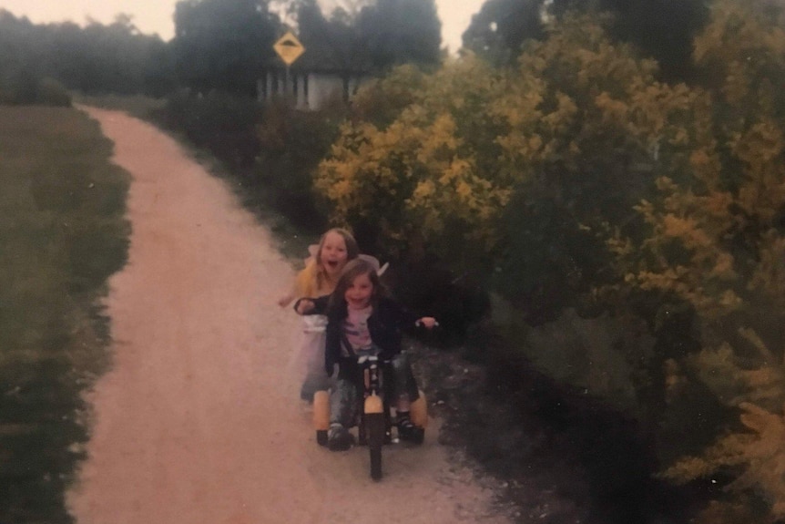 Julia Hunt and her sister Amelia, pictured as young girls, riding bikes around the neighbourhood.