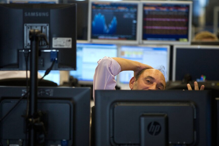 A bond trader partially obscured by his monitor