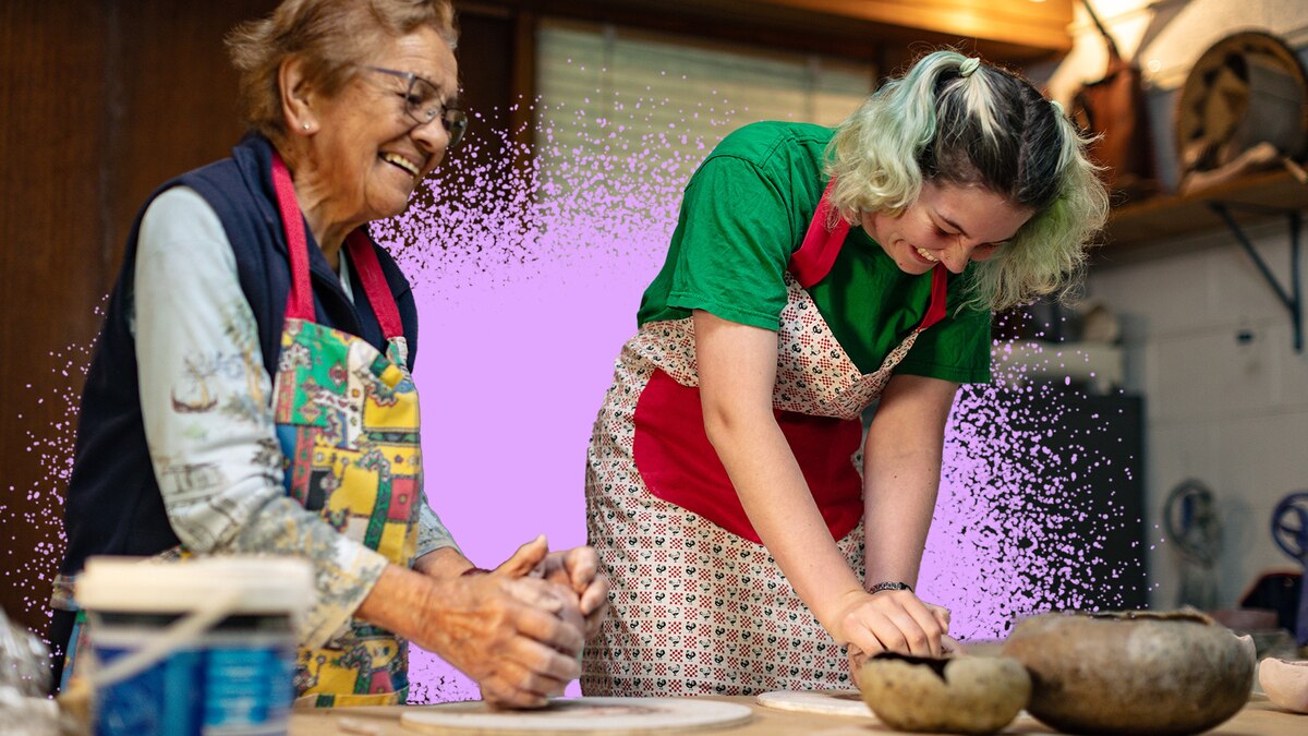Sally, left, smiles as she prepares clay in her hands on a table, next to Eden, who laughs as she looks down doing the same.