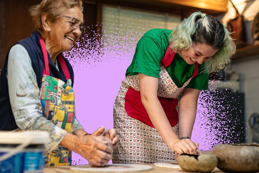 Sally, left, smiles as she prepares clay in her hands on a table, next to Eden, who laughs as she looks down doing the same.