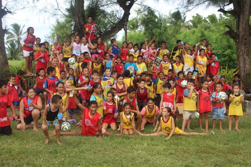 A large group of kids pose for a photo, including splashing water and doing the splits