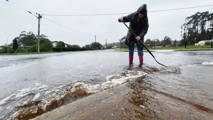 A woman stands gumboots in flowing water