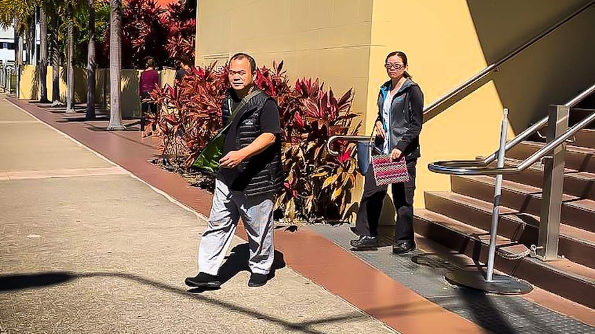 Man and woman walking down steps in front of Mackay court.