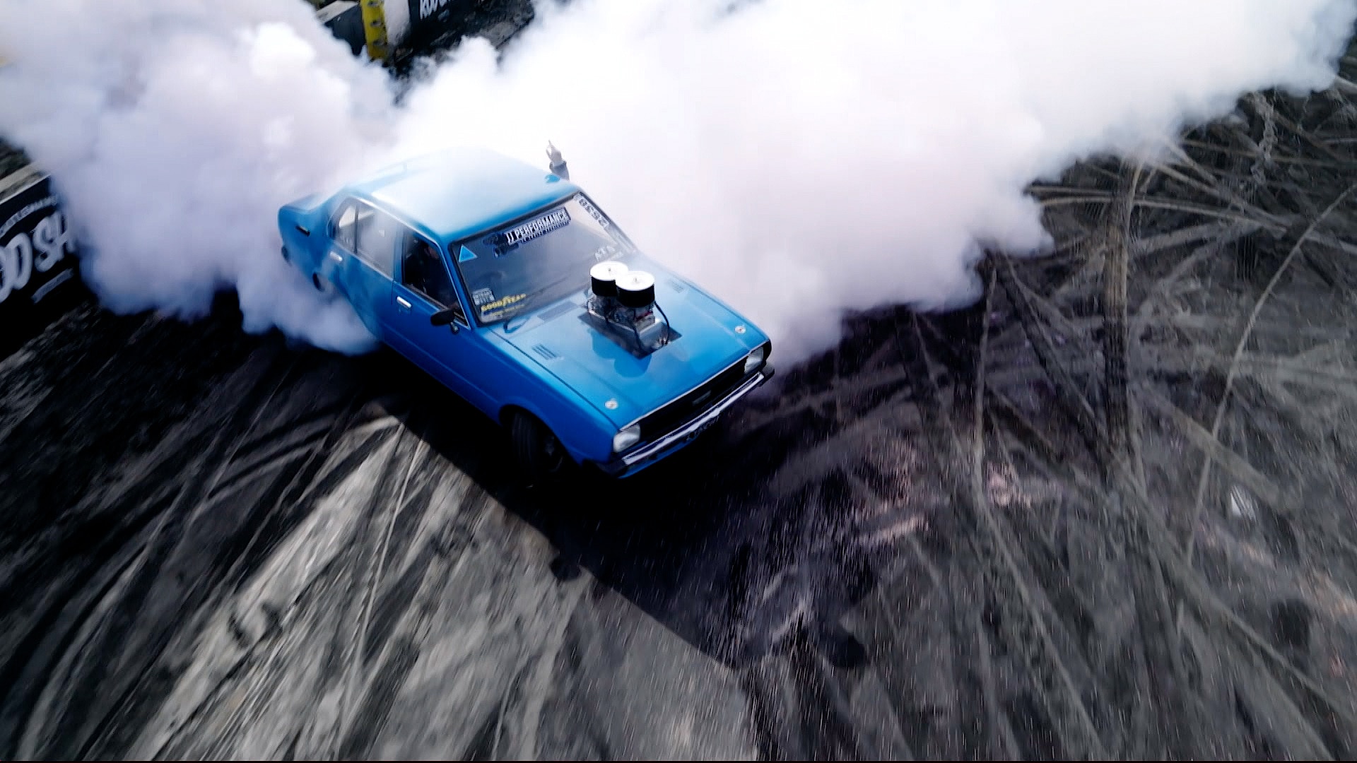 Um carro azul com fumaça saindo por trás. 