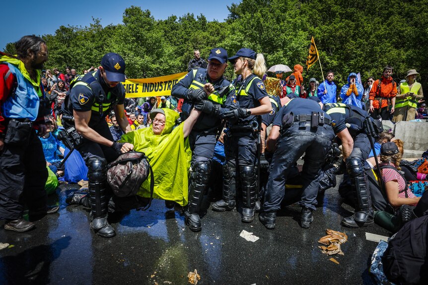 Police arrest climate protesters wearing waterproof jackets.