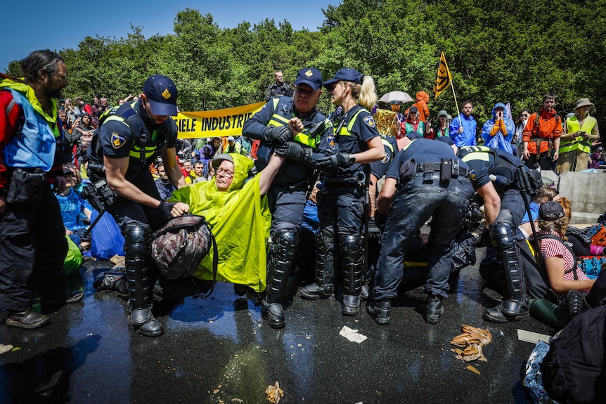 Police arrest climate protesters wearing waterproof jackets.