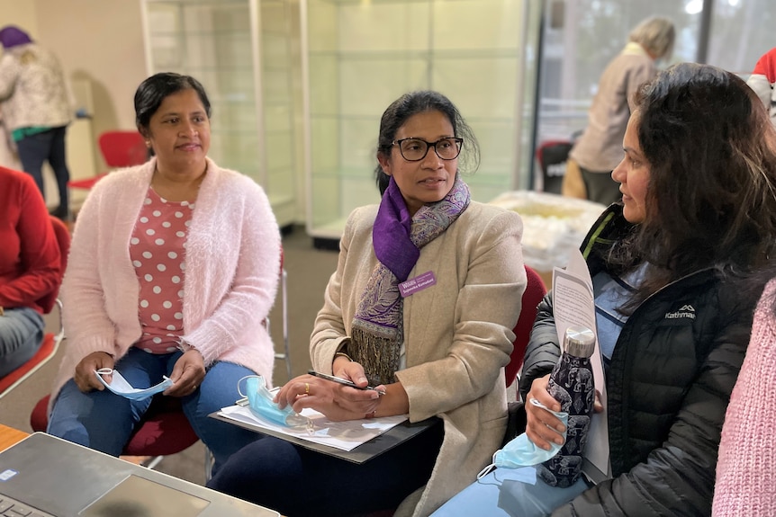 Three women sit together chatting