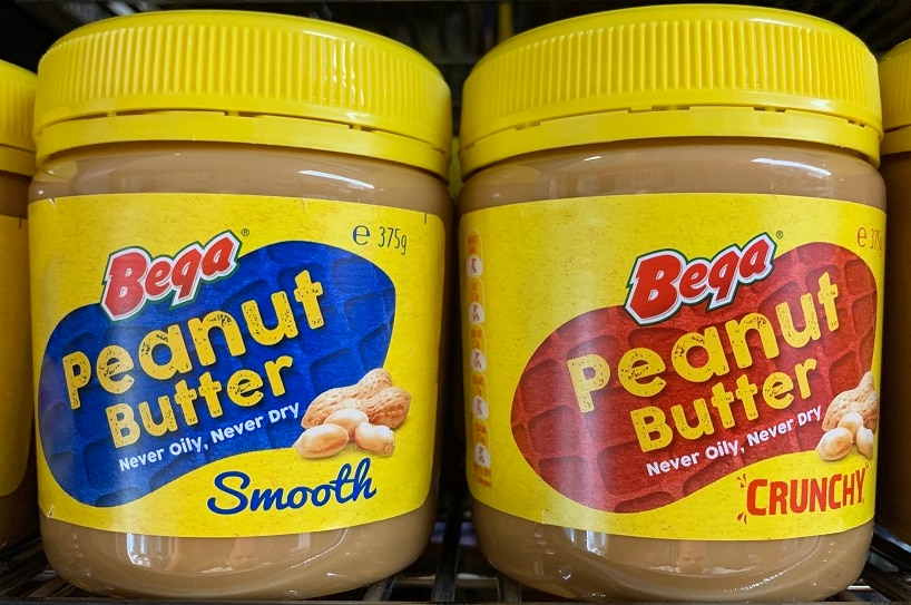 a row of peanut butter jars, two smooth and two crunchy, bear the 'bega' brand.