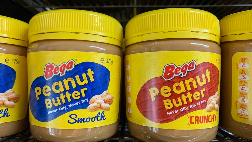 a row of peanut butter jars, two smooth and two crunchy, bear the 'bega' brand.