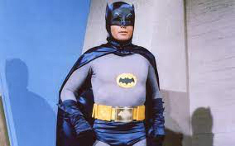 A grainy photo of Batman in a 1960s TV series: wearing a grey suit and black cape