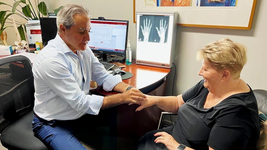 Dr examining woman's hands in clinic