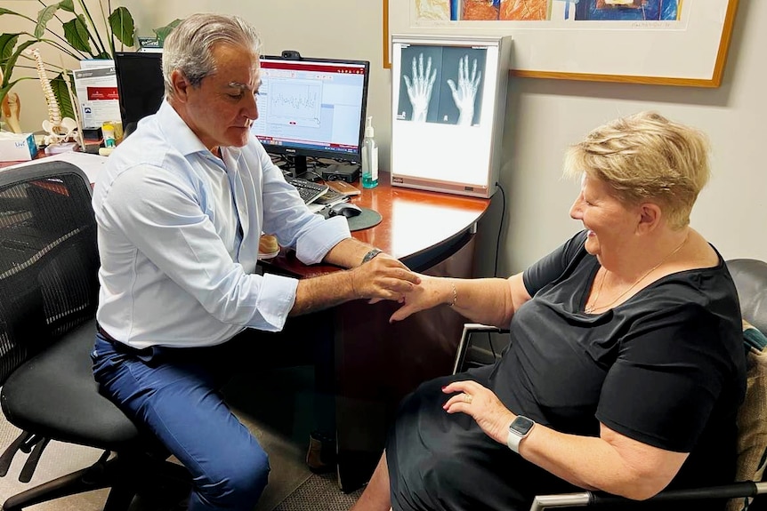 Dr examining woman's hands in clinic