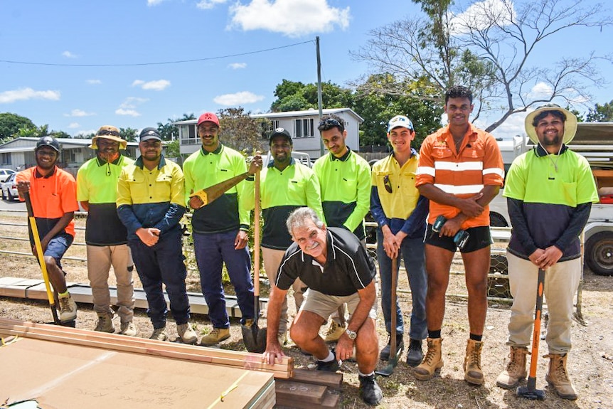 Young men wearing high-viz shirts and holding building tools on a building site