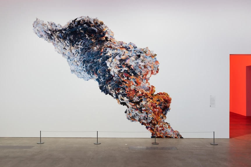 A plume of purple and red smoke, collaged on a wall from other images of fire and civil unrest