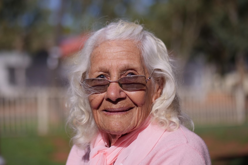 An old Aboriginal woman with sunglasses and white hair. 