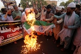A group of people burning a representation of an Indian flag.