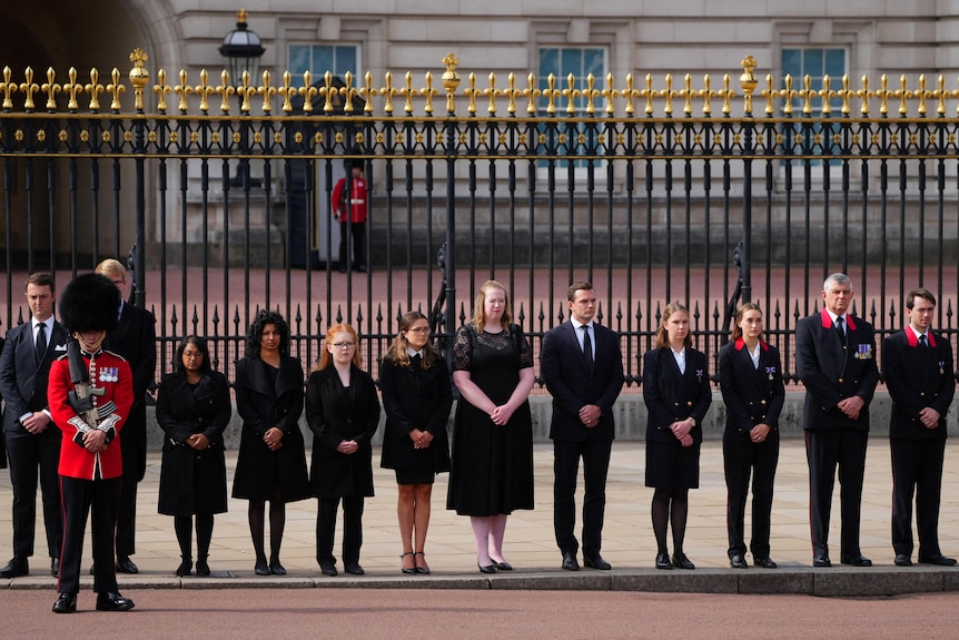 Buckingham Palace staff line the street at the Queen's hearse drives past