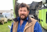 A man about forty years old, with brown hair and a brown scrubby beard smiling at the camera.