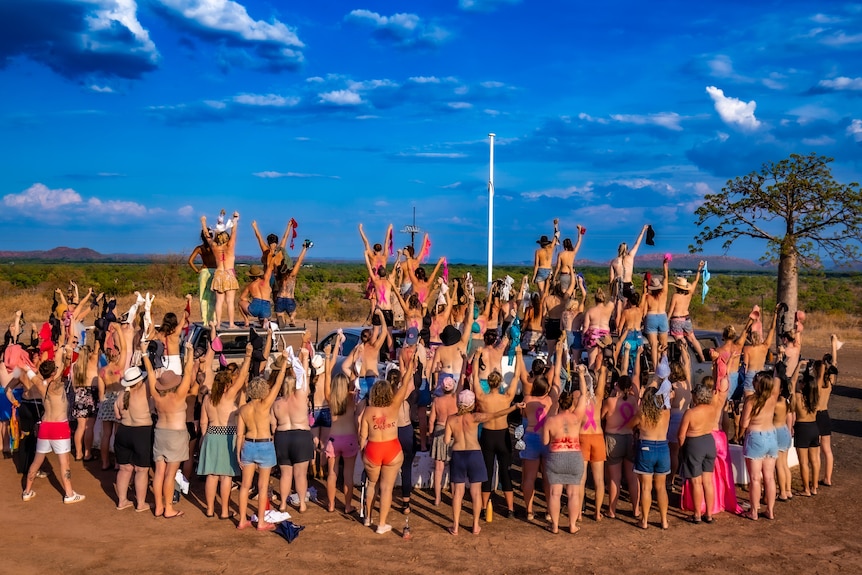 A group of woman face away from the camera with their tops off