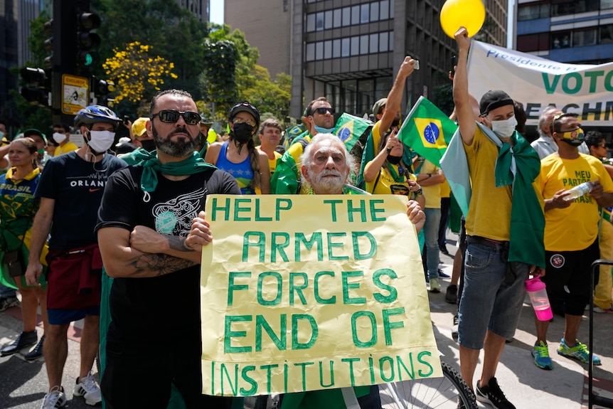 Supporters hold a sign reading: HELP THE ARMED FORCES END OF INSTITUTIONS