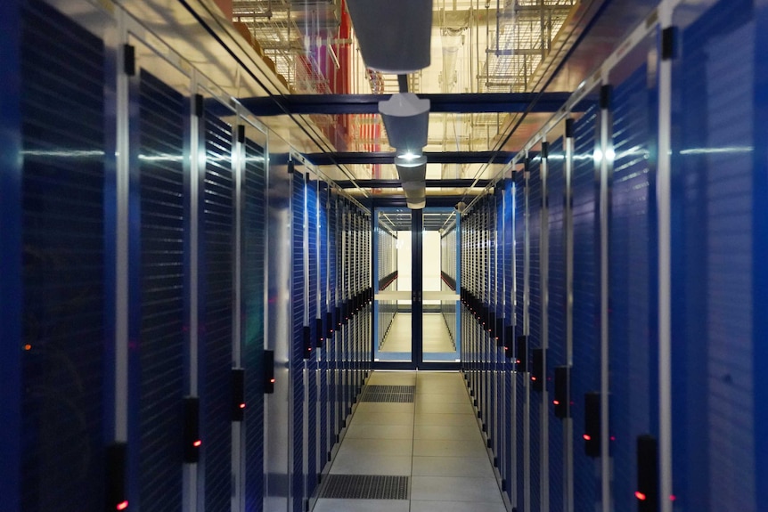 Two rows of servers in a dark room.