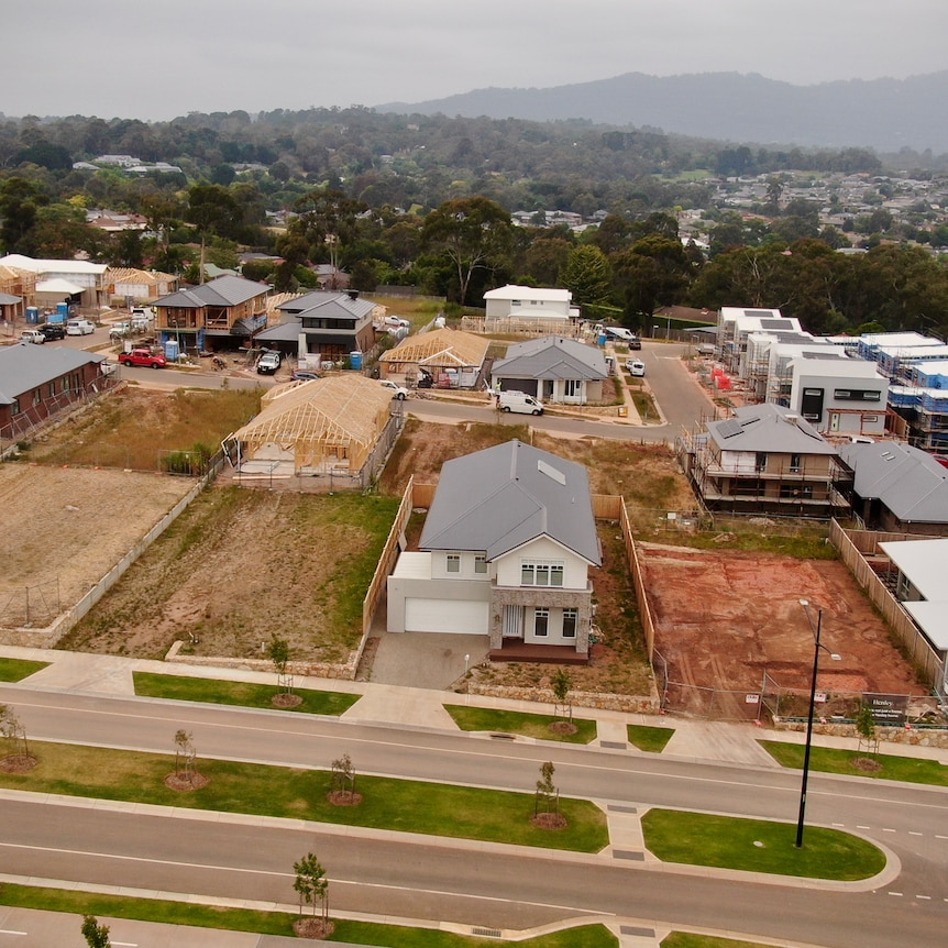 An aerial photo of a new housing estate with empty blocks and several new houses being built.