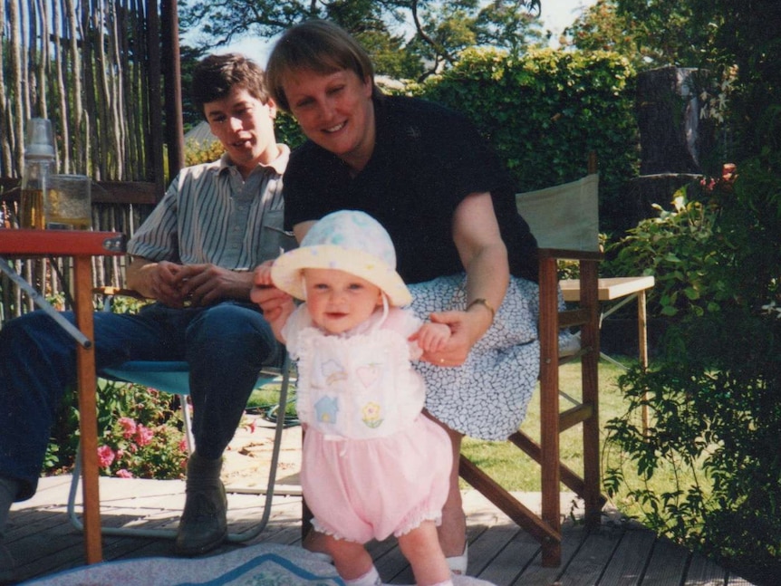 A man and woman outside with a baby on a rug