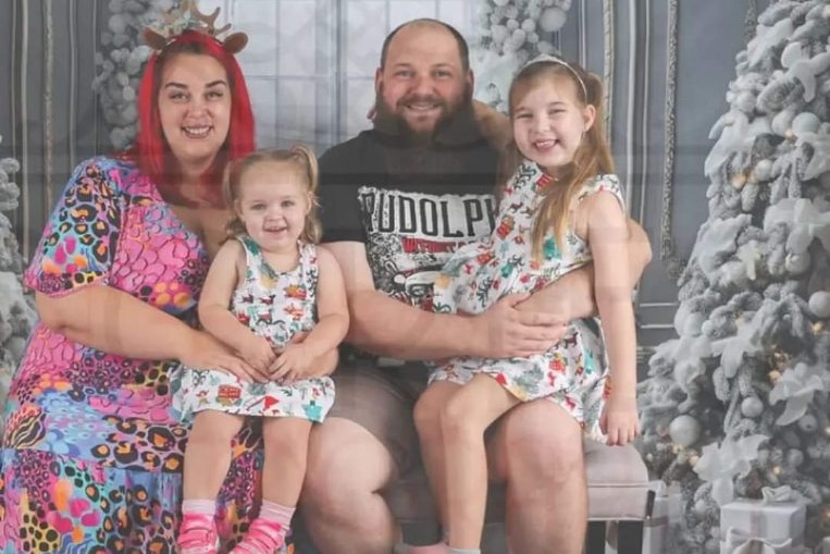 A mother, father and two children smile at the camera