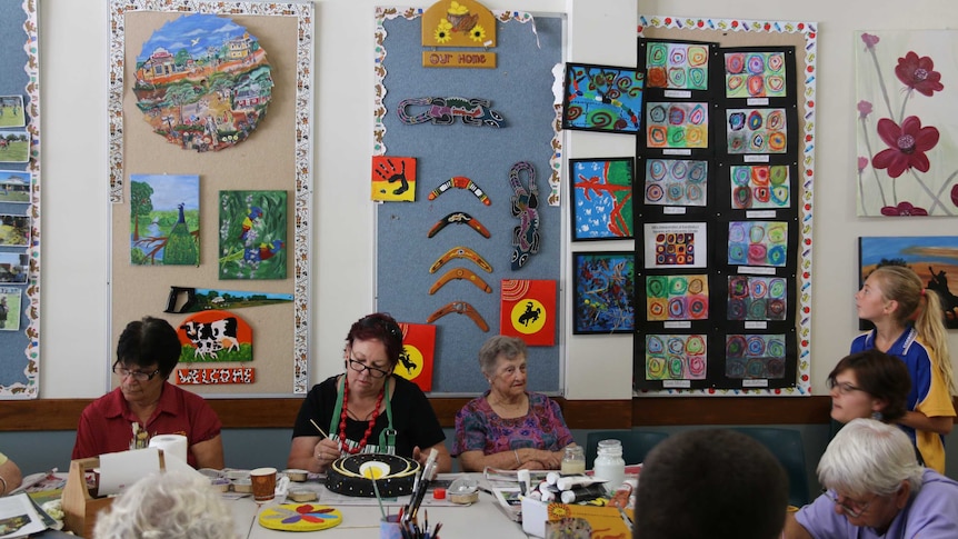 People of various ages work on craft projects in a Connected Communities shop front at Coonamble.