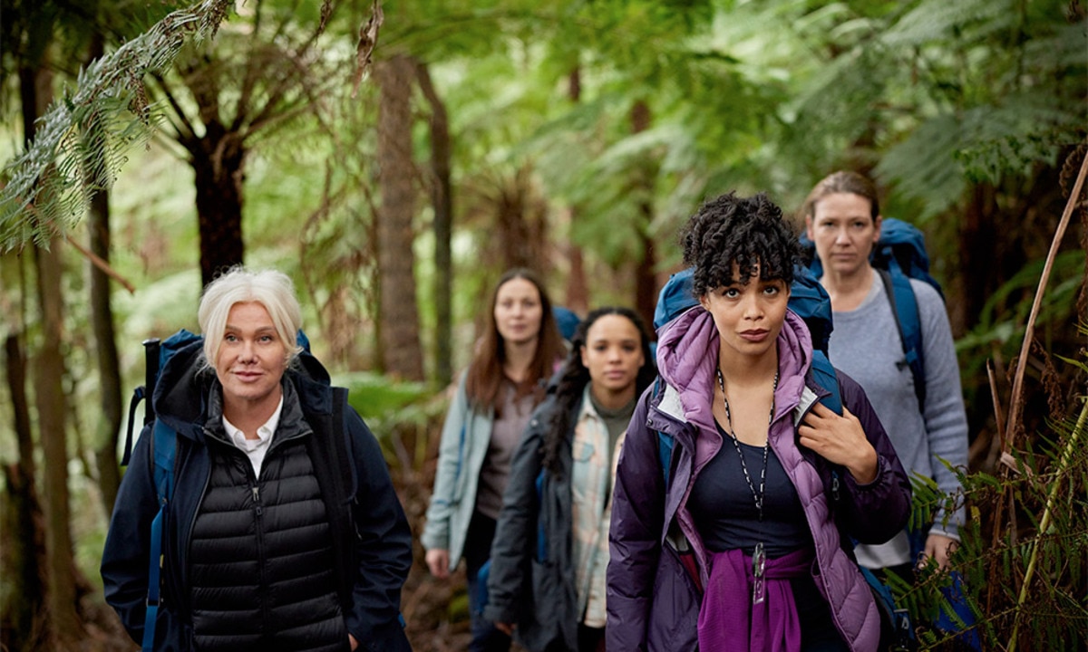 A group of five women hiking together with backpacks and warm clothes on in the Australian bush.