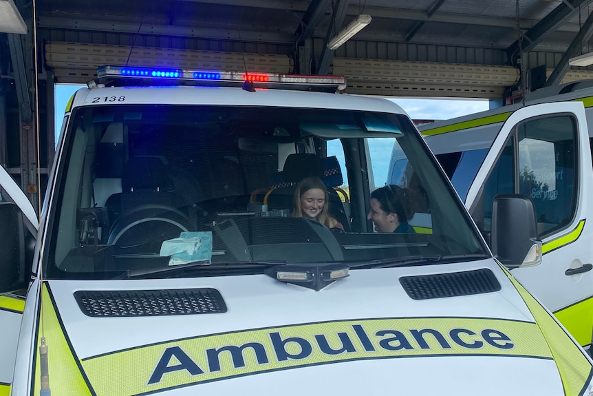 A young girl sits in the front seat of an ambulance