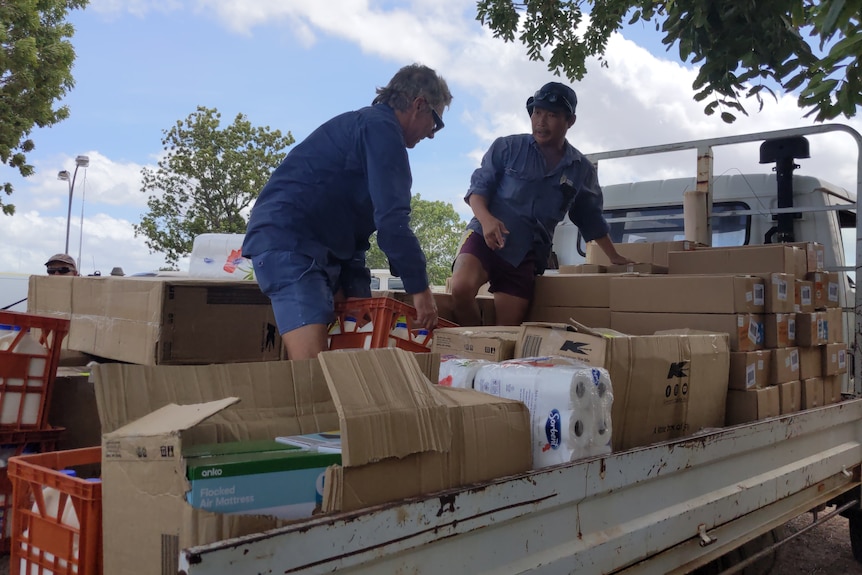 Two men remove boxes of supplies from the back of a truck.