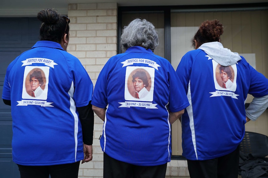 Buddy's family turn their backs to the camera to show a portrait of the teenager printed on their shirts.