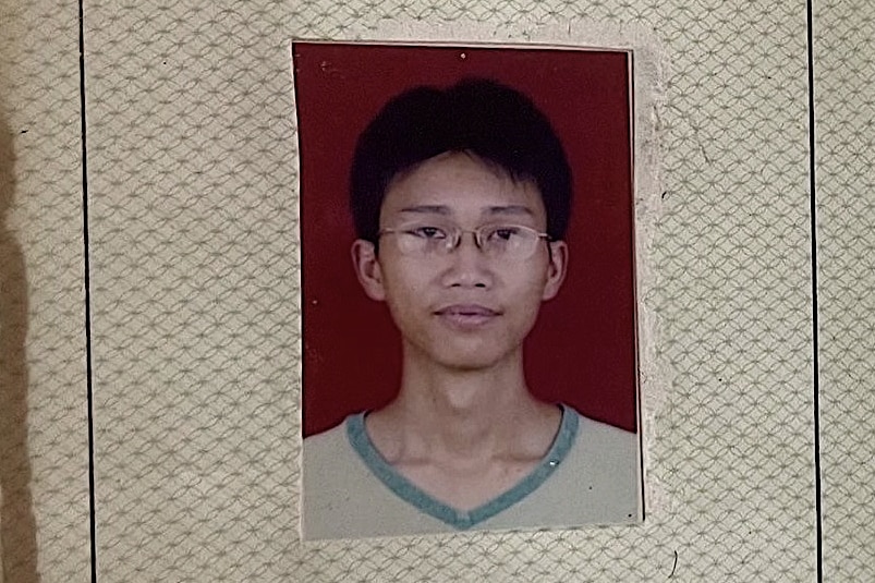 A pasport style photo of a young man in a T-shirt and glasses