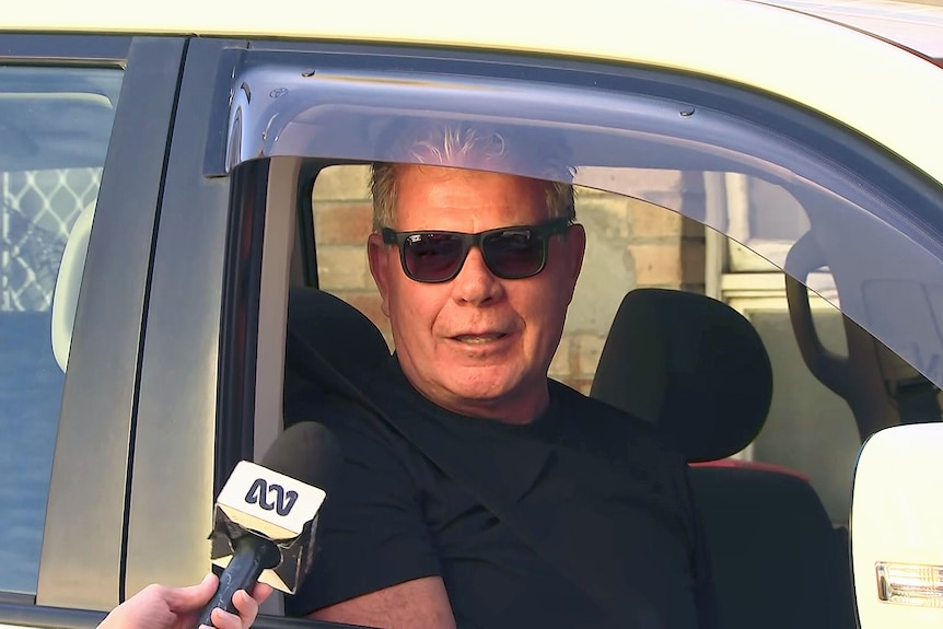 a man wearing glasses sits inside a car while being interviewed by an abc journalist 