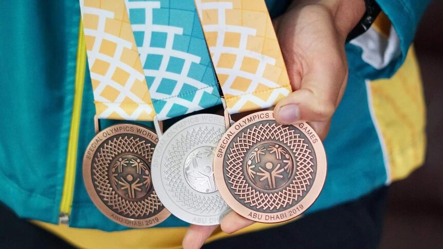 A close-up shot of two bronze medals and one silver medal with the words inscribed: Special Olympics World Games Abu Dhabi 2019.
