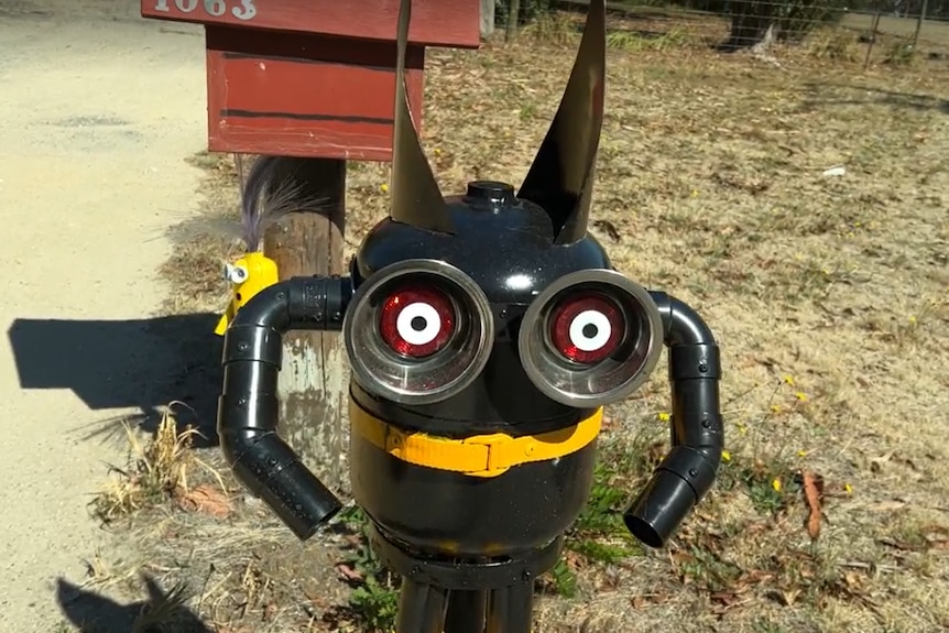 A minion sculpture of batman in front of a smaller actual minion.