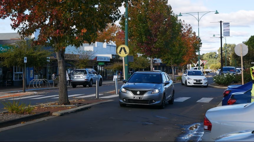 Un coche circula por la calle principal de Collie, con tiendas al fondo.