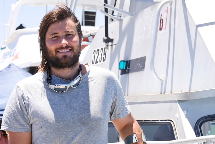 A man stands in front of a boat