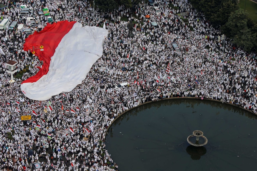 Members of hardline Muslim groups hold a big national flag