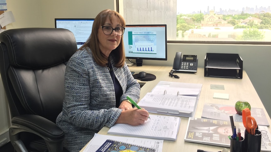 Robyn Erskine, a partner at insolvency firm Brooke Bird, writes at her desk in front of a computer.