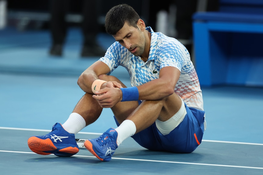 Novak Djokovic sits on the court on Rod Laver Arena after taking a fall.