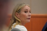 A blonde woman is pictured in a courtroom looking over her right shoulder. 