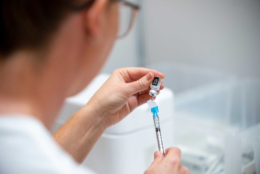 A health worker draws some of the Pfizer coronavirus vaccine from a vial with a syringe.