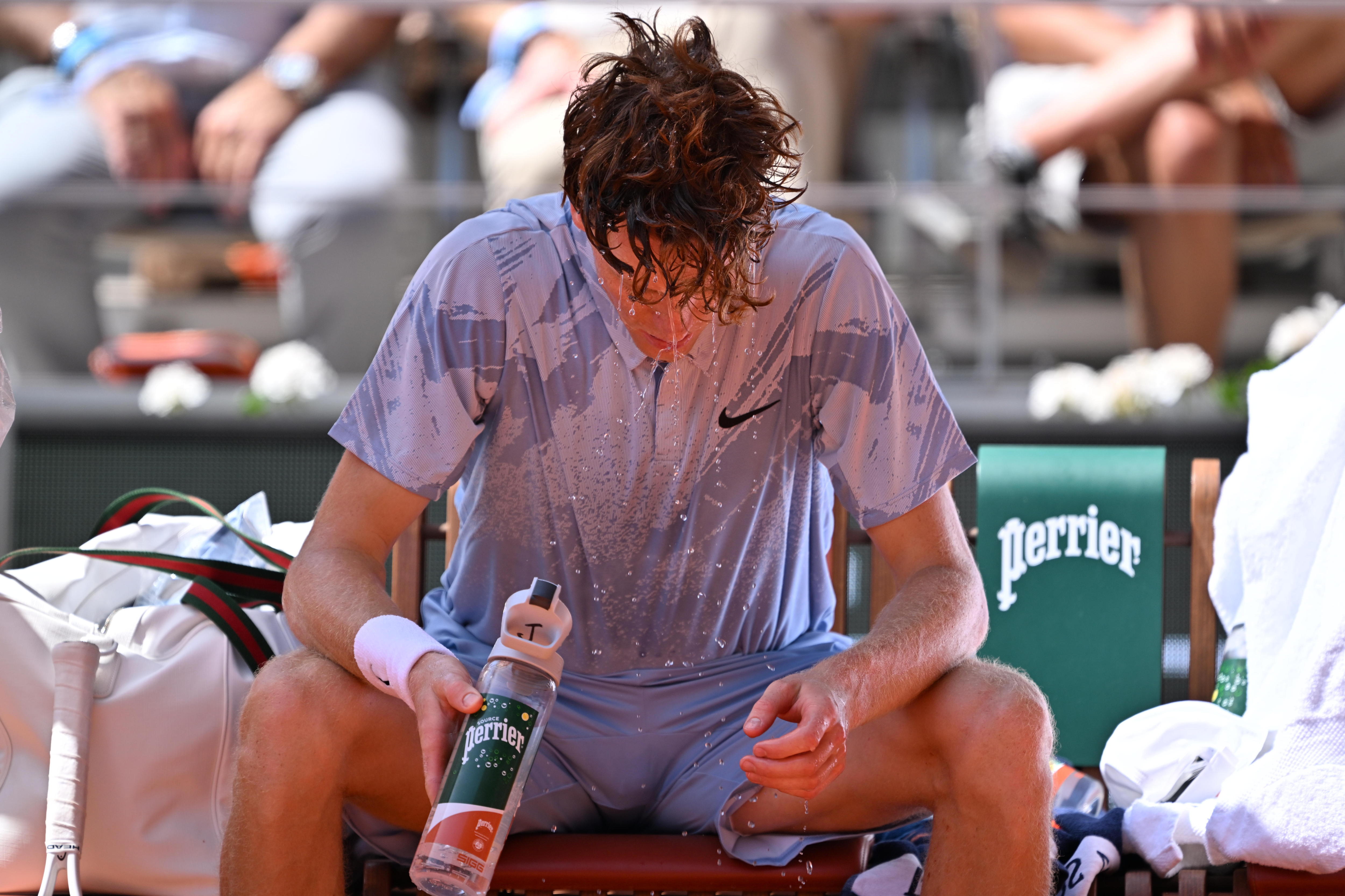 Jannik Sinner pours water over his head during a change of ends at the French Open.