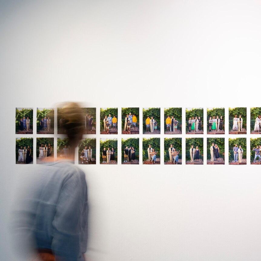 Woman in art gallery looking at a series of photos on a wall